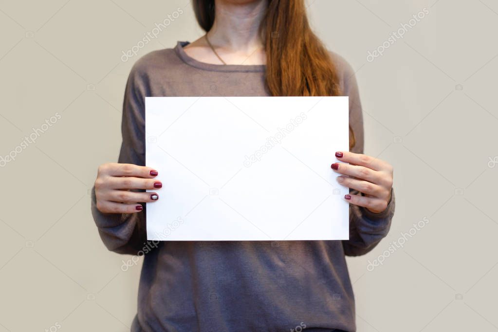 Girl holding white A4 blank paper vertically. Leaflet presentati