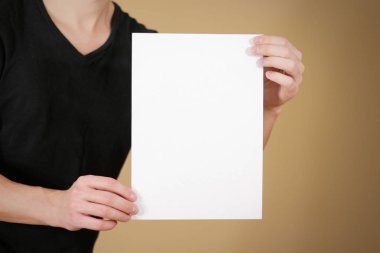 Boş beyaz A4 kağıt tutan siyah tişörtlü adam. Broşür prese