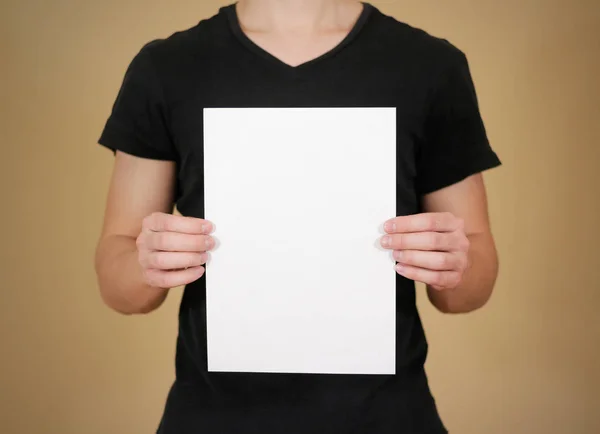 Homem de t-shirt preta segurando papel A4 branco em branco. Prese do folheto — Fotografia de Stock