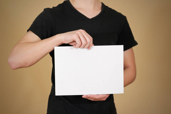 Man in black t shirt holding blank white A4 paper. Leaflet prese