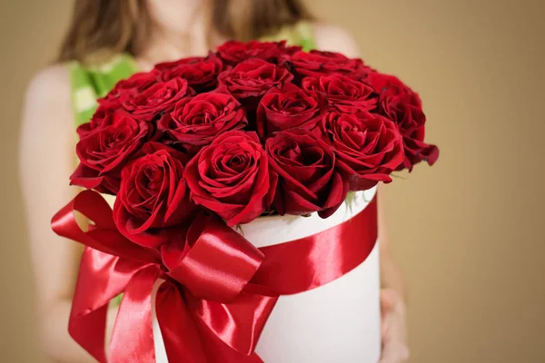Kız 21 kırmızı gül buketi el zengin hediye tutarak siyah ceketli. Kompozisyon bir beyaz şapka çiçek dolu. Geniş kırmızı kurdele ve yay ile bağlı.