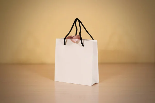 Leere Geschenktasche aus weißem Papier mit einer Schleife, die auf einem Holz steht — Stockfoto