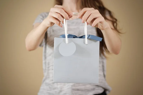 Дівчина тримає в руці порожній синій паперовий подарунковий пакет сміється. Порожня па — стокове фото
