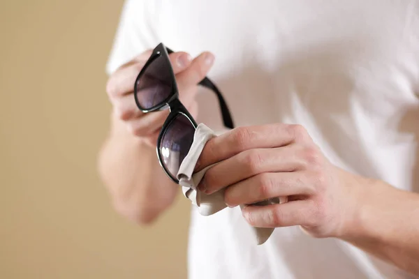 Человек в белой футболке рука чистки черных солнцезащитных очков линзы с i — стоковое фото
