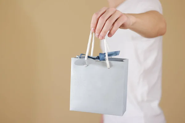 Hombre sosteniendo en la mano en blanco bolsa de regalo de papel azul se burlan. Vacío pac —  Fotos de Stock