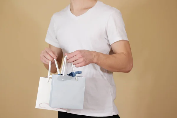 Hombre sosteniendo en la mano en blanco dos bolsa de regalo de papel se burlan. Envase vacío —  Fotos de Stock