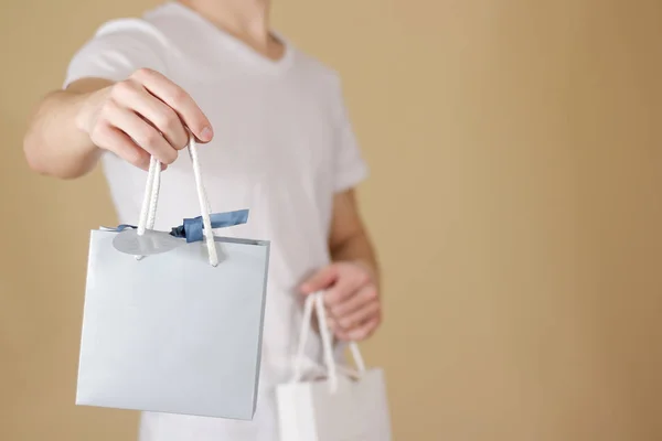Hombre sosteniendo en la mano en blanco dos bolsa de regalo de papel se burlan. Envase vacío —  Fotos de Stock