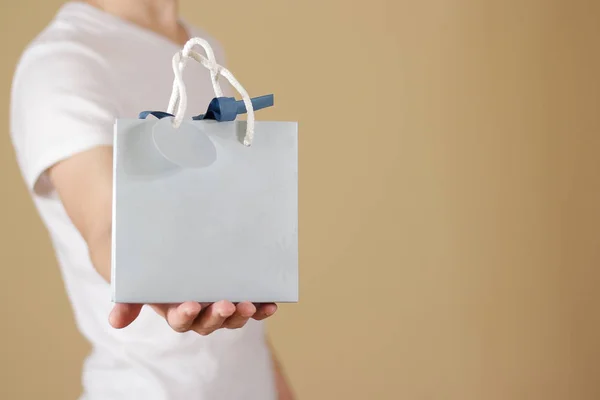 Hombre sosteniendo en la mano en blanco bolsa de regalo de papel azul se burlan. Vacío pac —  Fotos de Stock
