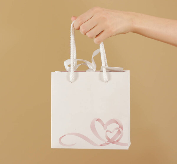 Blank white paper gift bag with hearts mock up holding in hand. 