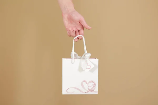 Bolsa de regalo de papel blanco en blanco con corazones simulados sosteniendo en la mano . —  Fotos de Stock