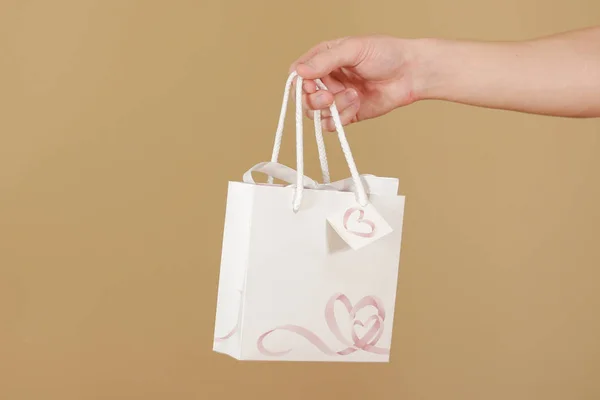 Пустой белый бумажный подарочный пакет с сердечками макет держа в руке . — стоковое фото