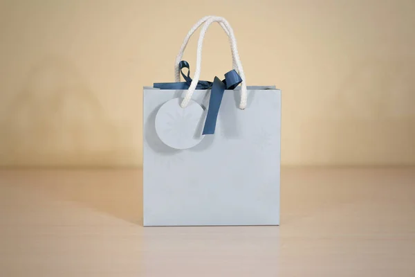 Bolsa de regalo de papel azul en blanco maqueta de pie sobre una mesa de madera. Em. —  Fotos de Stock