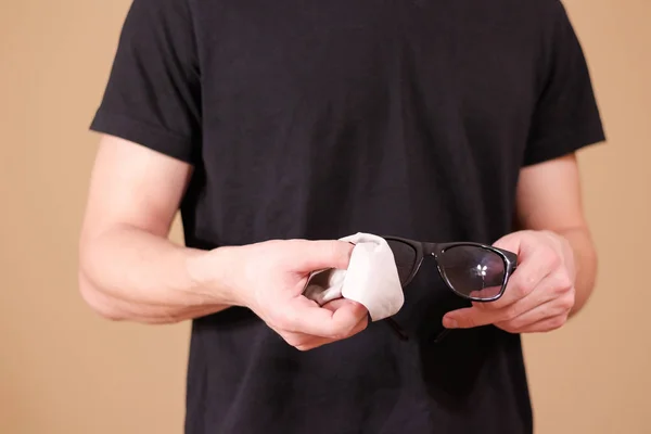 Мужчина вручную чистит линзы черных солнцезащитных очков с изолированной спинкой — стоковое фото
