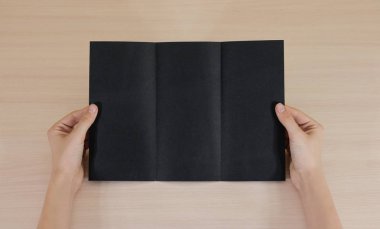 Boş siyah broşür kitapçık elinde tutan eller. Firma broşürü kapak sayfası 