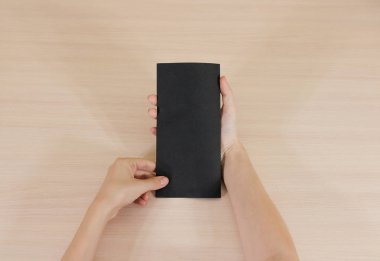 Boş siyah broşür kitapçık elinde tutan eller. Firma broşürü kapak sayfası 