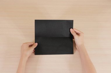 Boş siyah broşür kitapçık elinde tutan eller. Firma broşürü kapak sayfası 