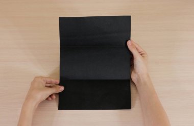 Boş siyah broşür kitapçık elinde tutan eller. Firma broşürü kapak sayfası 