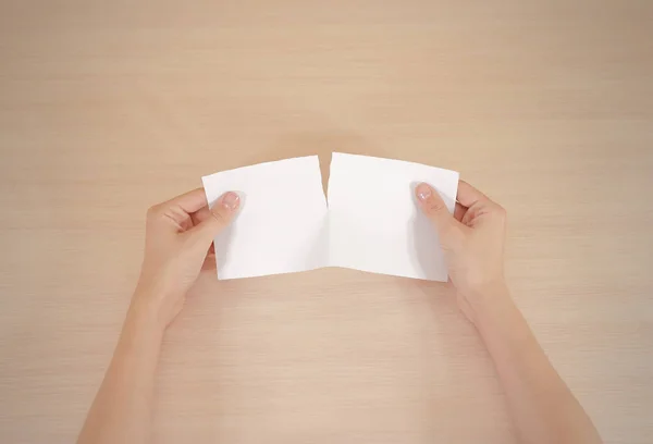 Manos rasgando un pedazo de papel en brochur volante blanco medio en blanco — Foto de Stock