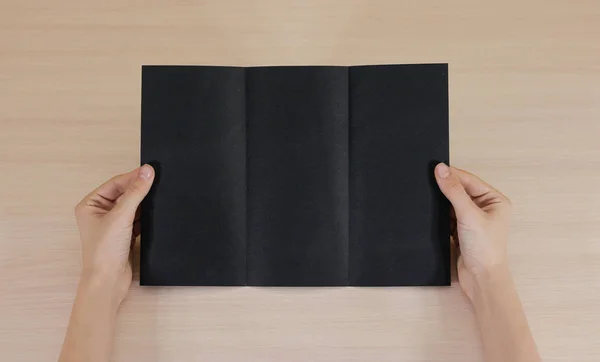 Boş siyah broşür kitapçık elinde tutan eller. Firma broşürü kapak sayfası — Stok fotoğraf