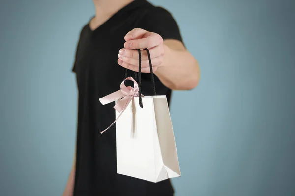 Мужчина держит в руке пустой белый бумажный подарочный пакет макет. Пустой па — стоковое фото