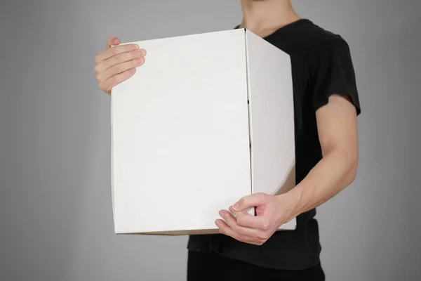 Il tizio con la camicia nera con una grande scatola bianca. Trasporta un Fotografia Stock