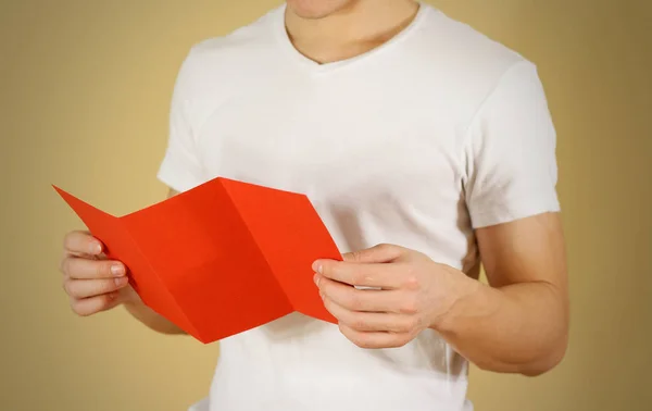 Homem a ler panfleto vermelho em branco. Leia o folheto detalhado. Lea. — Fotografia de Stock