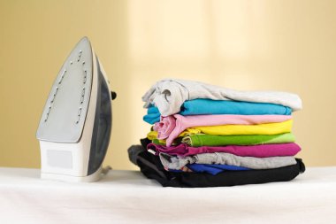 Demir ütülenmiş renkli keten Baca'ya duruyor. Elbise yığını