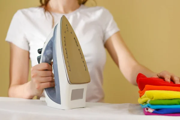 Primer plano de la mujer planchando ropa de color en la tabla de planchar. Casa — Foto de Stock