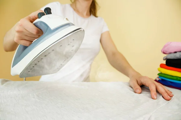 Primer plano de la mujer planchando ropa de color en la tabla de planchar. Casa — Foto de Stock