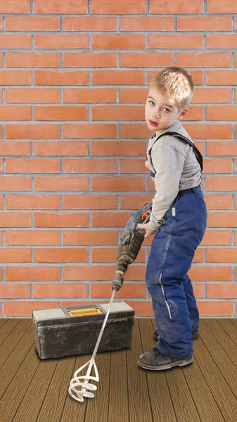 Niño con la herramienta de construcción. Está en el suelo en la pared de ladrillo — Foto de Stock