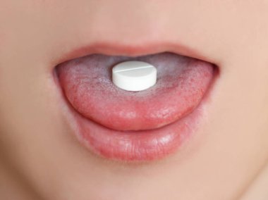 Erkeğin ağzına beyaz bir hap close-up. Yuvarlak tablet üzerinde th