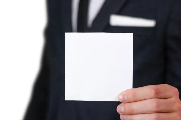 Un homme d'affaires montre du papier blanc carré, gros plan. Affichage flye vierge — Photo