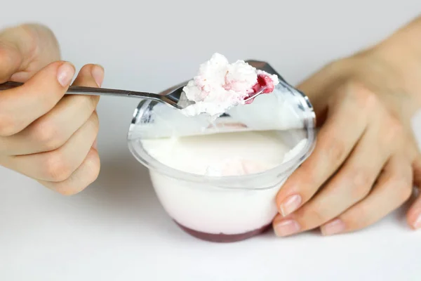 A mão da menina mexeu com uma colher de iogurte natural e geléia vermelha . — Fotografia de Stock