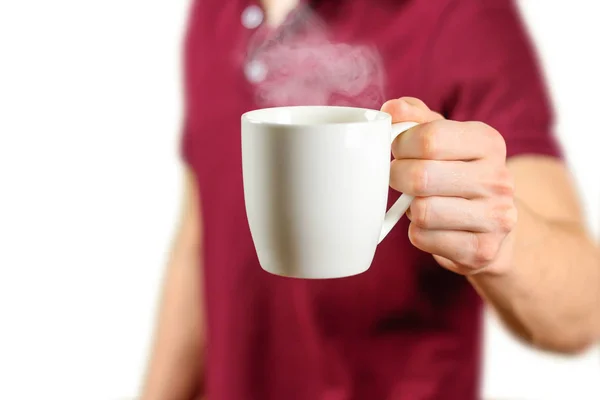 The man in the red shirt shows a clean white Cup. Cup for your d — Stock Photo, Image