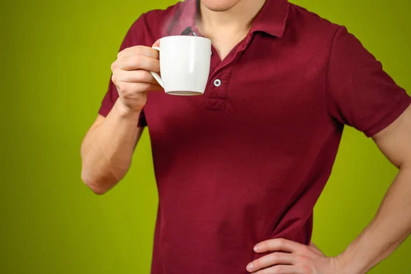L'uomo con la camicia rossa mostra una tazza bianca pulita. Coppa per il tuo d — Foto Stock