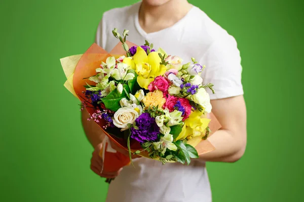 Jovem com uma camisa branca segurando um lindo buquê de flor — Fotografia de Stock