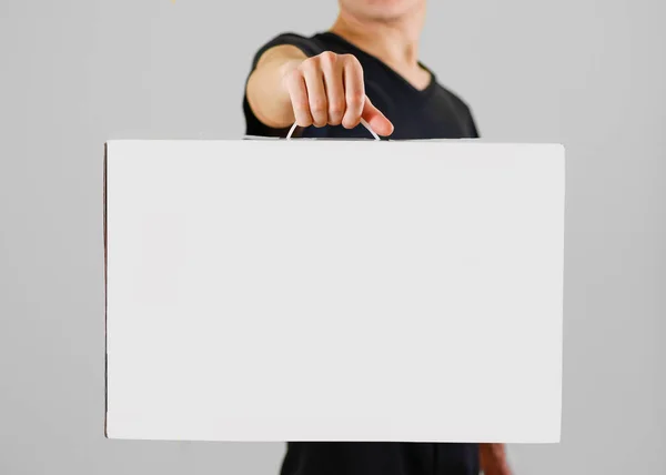 Homem de camisa preta segura uma caixa branca com uma alça. Embalagem bo — Fotografia de Stock