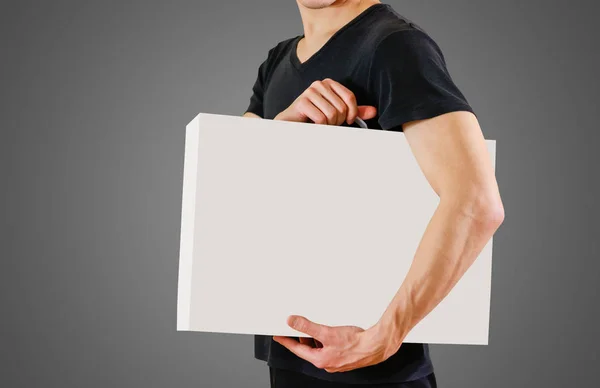 Мужчина в чёрной рубашке держит белую коробку с ручкой. Packing bo — стоковое фото