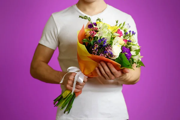 Young guy in a white shirt holding a beautiful bouquet of flower — Stock Photo, Image