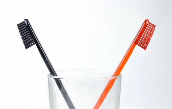 Closeup of two toothbrushes in a glass beaker. For men and women — Stock Photo, Image