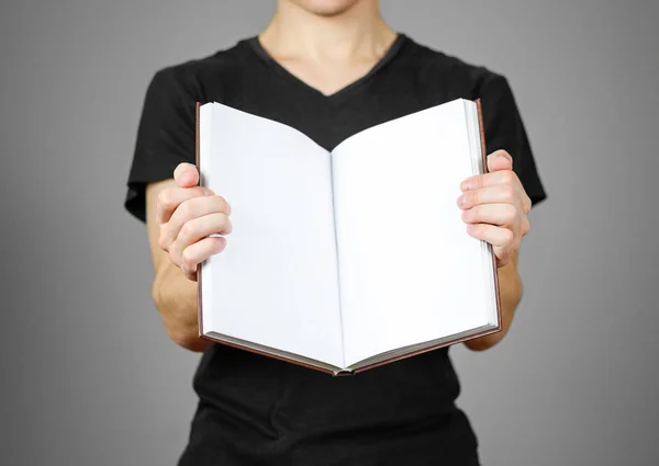 Fechar-se de cara em t-shirt preta segurando em branco livro branco aberto em — Fotografia de Stock