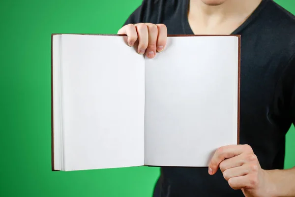 Closeup of guy in black t-shirt holding blank open white book on