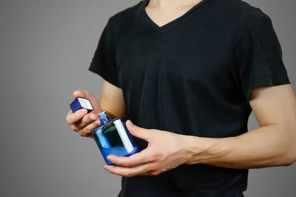 Man in het zwart t shirt blauw fles toilet water te houden. Close-up, — Stockfoto