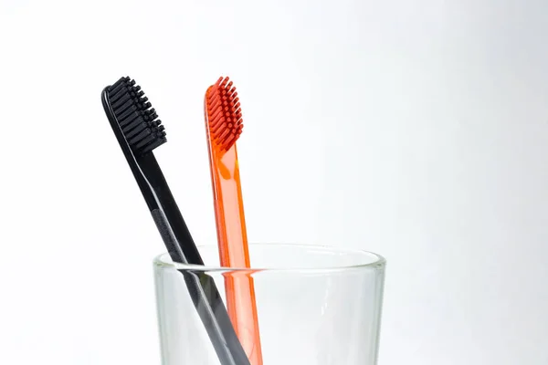 Крупный план двух зубных щеток в стеклянном стакане. Для мужчин и женщин — стоковое фото