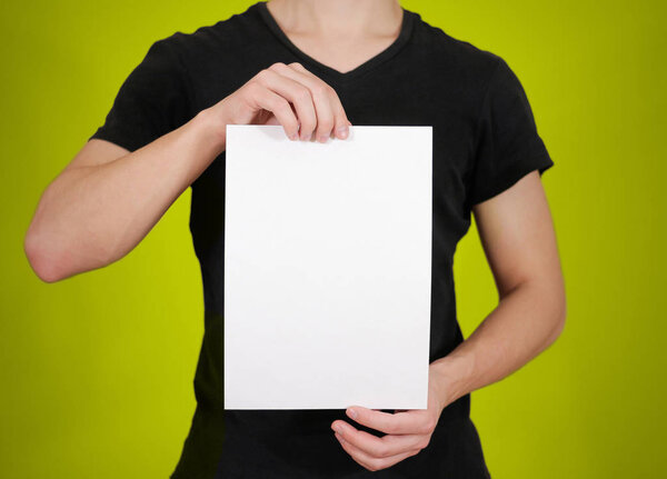 Man in black t shirt holding blank white A4 paper. Leaflet prese