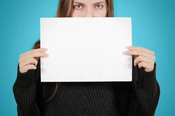 Chica sosteniendo papel blanco A4 en blanco. Cubre la cara, la boca y no — Foto de Stock