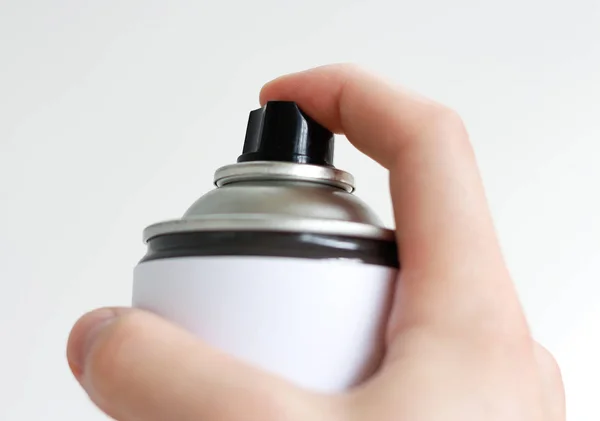 Man's hand holds a spray of black paint. Isolated on a white bac — Stock Photo, Image