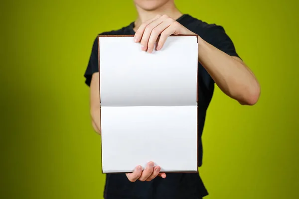 Крупним планом хлопець в чорній футболці тримає порожню відкриту білу книгу на — стокове фото