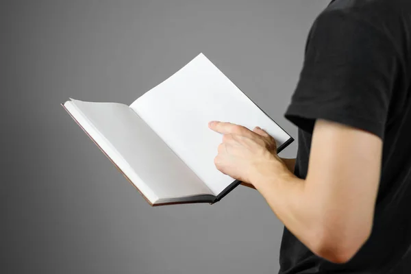 Närbild av killen i svart t-shirt håller tomt öppen vit bok — Stockfoto