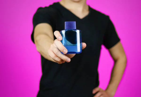 Ο άνθρωπος στη μαύρη μπλούζα κρατώντας μπλε μπουκάλι νερό τουαλέτας. Κοντινό πλάνο, — Φωτογραφία Αρχείου